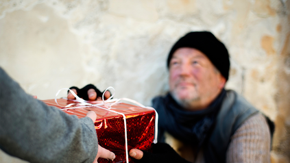 Obdachlosem wird rot verpacktes Weihnachtsgeschenk überreicht.