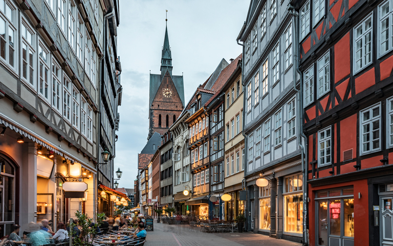 Abendlich beleuchtete Kramerstraße in der historischen Altstadt Hannovers mit Fachwerkhäusern und der Marktkirche im Hintergrund