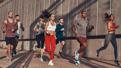 Junge Menschen joggen gemeinsam an einer Wand entlang. Vier Männer und 3 Frauen.