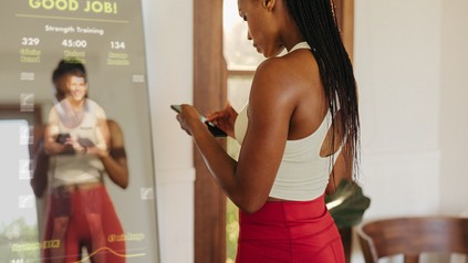 Junge Frau nutzt nach dem Training eine Fitness-App auf ihrem Smartphone.