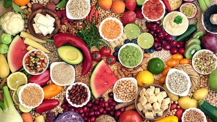 Verschiedene Früchte und andere vegane Lebensmittel zusammen auf einem Tisch drapiert und von oben fotografiert.