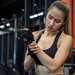 Junge Frau in Sportklamotten im Fitnessstudio, die sich das Handgelenk hält.