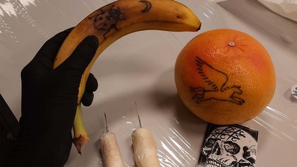 Auf dem Bild sind Anfänger-Tattoos auf einer Orange und Banane zu sehen.