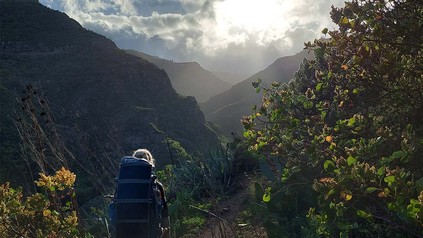 Auf dem Bild ist ein Mädchen mit ihrem Rucksack beim Wandern zu sehen.