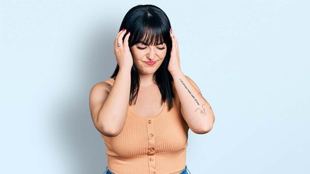 Junge dunkelhaarige Frau, die sich die Hände an den Kopf hält.