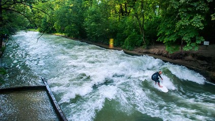 Mann in Neoprenanzug auf Surfwelle in München.