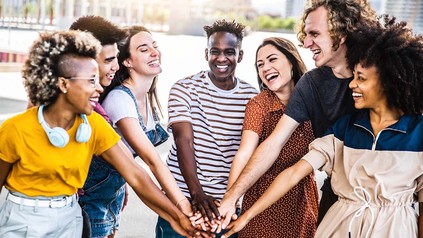 Diverse Studierende, die draußen im Halbkreis stehen und sich in die Hand schlagen.