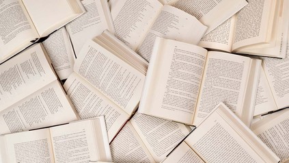 Viele aufgeklappte Bücher, die sich überlappen - von oben fotografiert.