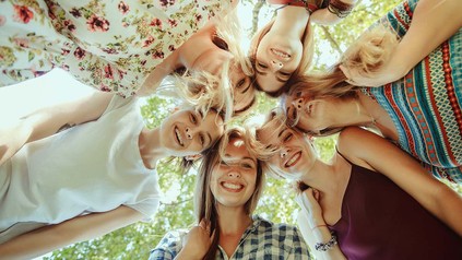 Junge Frauen, die im Kreis stehen und lächeln.