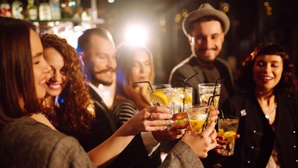 Freunde beim Anstoßen mit Mischgetränken in Bar.