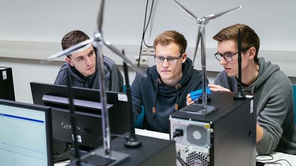 Drei Studenten im Computerraum vor Computer.