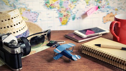 Landkarte, Fotoapparat, Sonnenbrille, Spielzeugflugzeug und Sonnenhut.