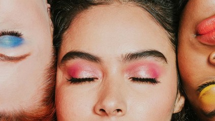 Nahaufnahme von den bunt geschminkten Gesichtern von drei Frauen.