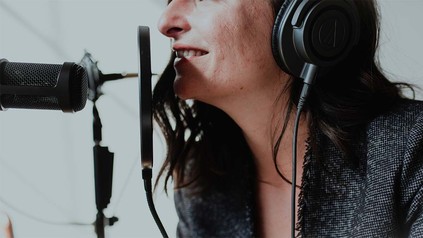 Brünette Frau spricht Podcast ein.