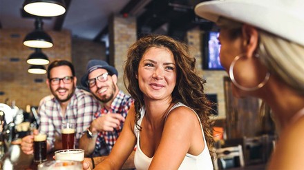 Zwei lächelnde Frauen und zwei Männer in einer Bar.