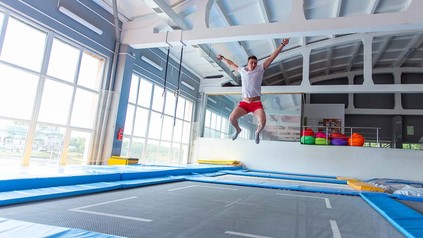 Junger Mann beim Indoor-Trampolinspringen.