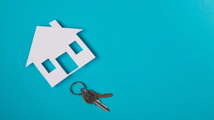 Nicht aufgepasst und jetzt ist der Wohnungsschlüssel weg? (Foto: © stock.adobe.com/Andrej Wilusz) Schlüssel und Haussilouette vor blauem Hintergrund.