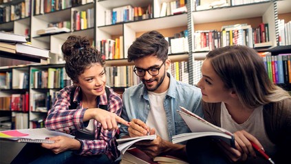 Drei Studierende in der Bibliothek beim gemeinsam Lernen.