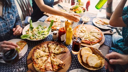 Junge Leute an Restauranttisch beim Pizzaessen.