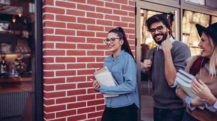 Gemeinsam anstatt alleine kann man viel mehr schaffen. (Foto: © stock.adobe.com/bernardbodo) Drei lächelnde Studierende, die über den Campus laufen.