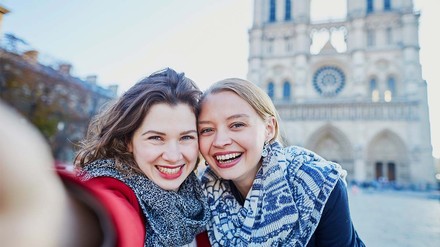 Frankreich, Spanien oder doch Italien? (Foto: © stock.adobe.com/Ekaterina Pokrovsky) Zwei fröhliche junge Frauen vor Notre Dame.