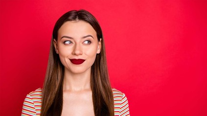 Junge Frau mit dunkelrotem Lippenstift vor rotem Hintergrund.