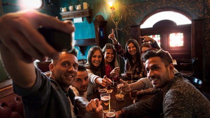 Gruppe junger Leute im Pub, die ein Selfie machen.
