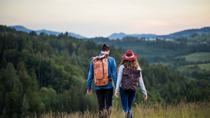 Zwei Studenten beim Wandern mit Aussicht auf die Berge, die vor ihnen liegen.