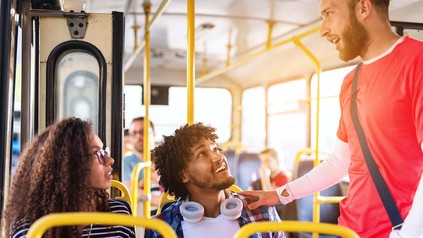 Drei junge Menschen, die sich im Bus unterhalten.