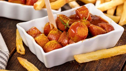 Currywurst in Keramikschale mit Pommes.