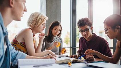Studierenden Gruppe an Tisch mit Büchern und Markern.
