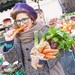 Studentin mit einer Papiertüte voller Gemüse und einer Karotte in der Hand auf dem Stadtmarkt.