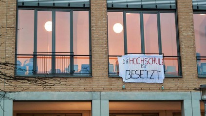 Sicht auf den Eingang des Hörsaalzentrums der Alice-Salomon-Hochschule Berlin mit Banner 'Die Hochschule ist besetzt'.