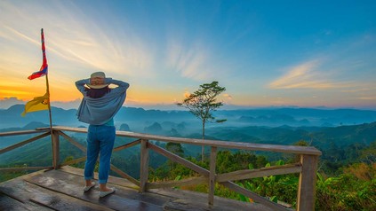 Junge Frau mit Sonnenhut steht auf Aussichtsplattform des Misty Mountain, Doi Ta Pang in Chumporn.