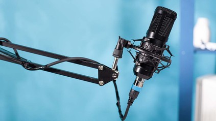 Nachaufnahme von Podcast-Mikrofon an Halterung vor blauem Hintergrund.