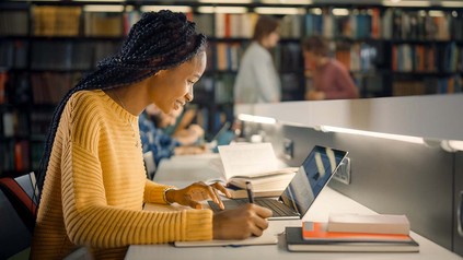 Studentin arbeitet mit ihrem Laptop an einem Arbeitsplatz in der Bibliothek.