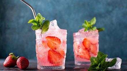 Cocktails mit frischen Erdbeeren sind besonders sommerlich. (Foto: © GettyImages/Olga Gagarova) Zwei schön mit Mustern verzierte Gläser Erdbeer-Mojito mit Minze angerichtet.