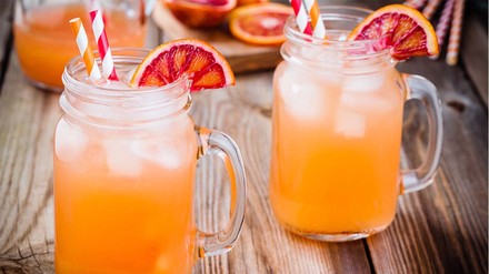 Zwei Limonadengläser voll mit Maracuja-Longdrink, dekoriert mit Blutorangenscheiben.