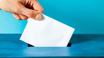 Ein Brief wird in die Wahlurne geschmissen.