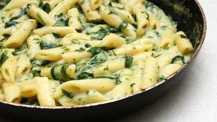 Spinatnudeln in einer dunklen Schüssel.