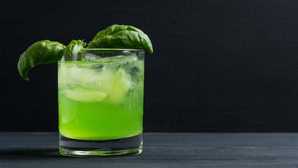 Bild von fertigem Cocktail in Glas, verziert mit frischen Basilikumblättern.