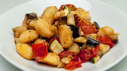 Gemüsepfanne mit Gnocchi in einem weißen Teller.