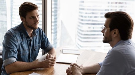 Junger Mann in Jeanshemd bei Beratungsgespräch.