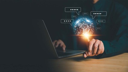 Torso vor Holzschreibtisch mit Laptop, reinretuschiertes Netz mit 'AI' Aufschrift.