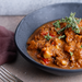 Gulasch in Schüsselchen auf Tisch, drapiert mit Grünzeug.