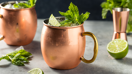 Schöne rosefarbene Cocktailtassen mit Irish Mule - dekoriert mit Limettenscheiben und frischer Minze.