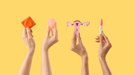 Vier Hände halten jeweils ein Kondom, eine Menstruationstasse, ein Eierstocksreplikat und einen Schwangerschaftstest
