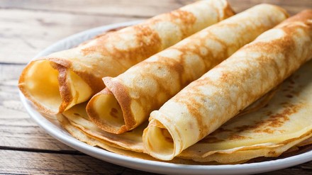 Pfannkuchen ausgeklappt und zusammengerollt auf einem Teller angerichtet.