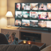 Junge Frau spät abends auf dem Sofa vor dem Fernseher, auf dem ein Streaminganbieter läuft.