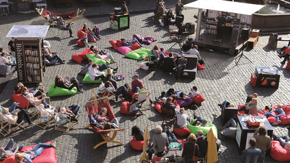 Sicht auf den Bebelplatz in Berlin, auf dem Menschen in Sitzsäcken und Händematten liegen/sitzen und lesen.